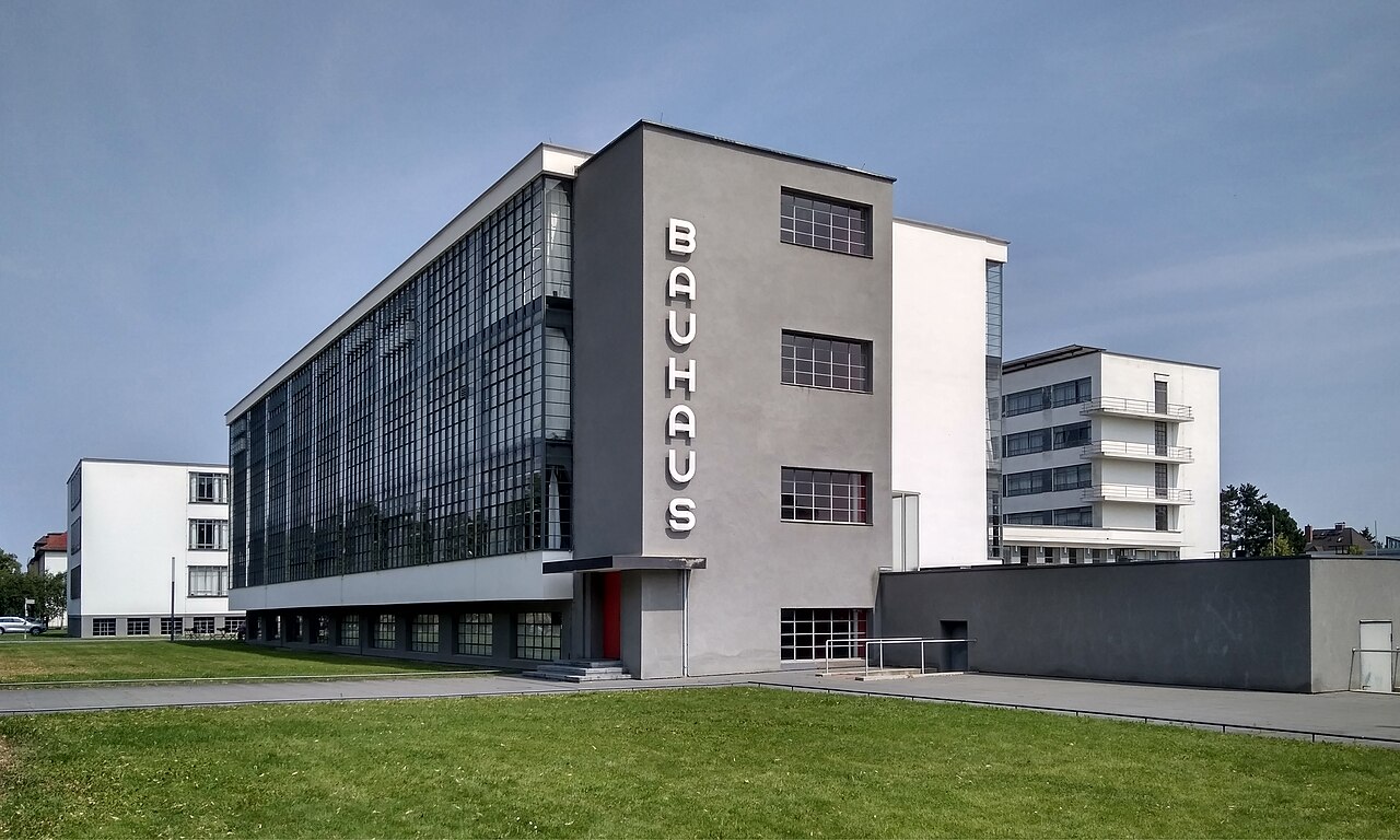 El edificio de la Bauhaus en Dessau: el ala de talleres cerrada
                  con un muro cortina de vidrio de tres plantas, con el rótulo
                  BAUHAUS en vertical.