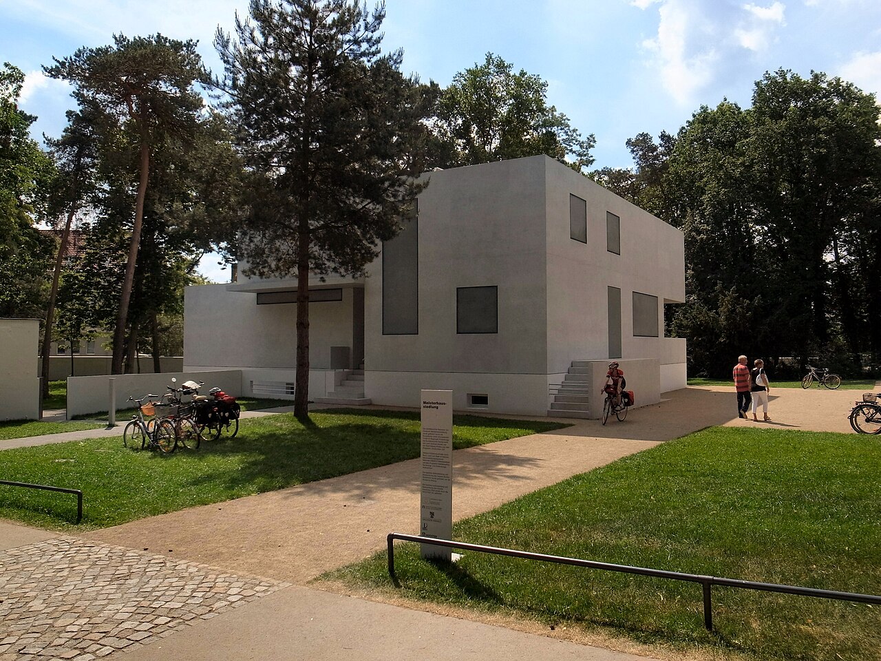 Una de las casas de los maestros de la Bauhaus en Dessau:
                  volúmenes blancos cúbicos entre los pinos, con ventanas
                  grandes y cubierta plana.