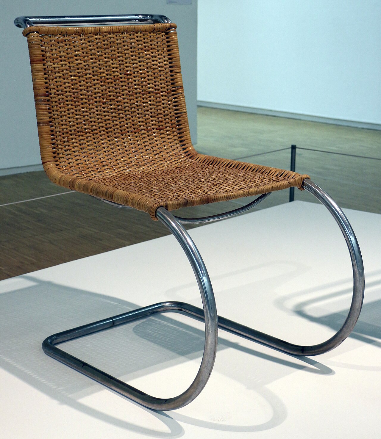La silla MR10 de Mies van der Rohe: un solo tubo de acero
                    que arranca del suelo en curva y sube sin patas traseras,
                    con asiento y respaldo de rejilla.